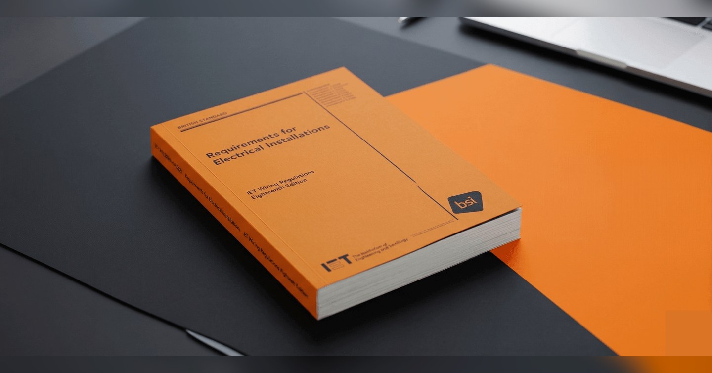 BS 7671:2018+A4:2026 Requirements for Electrical Installations, the orange book, on a desk